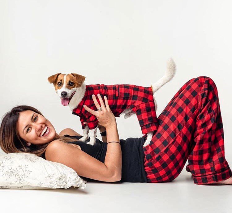 Kvinna i rödrutiga pyjamasbyxor med liten hund