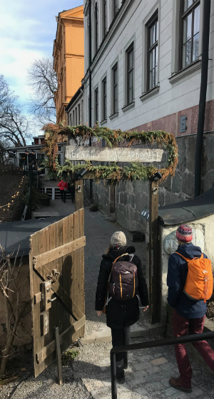 Besökare på väg in till den veganska restaurangen Hermans. En portal med texten Hermans trädgårdscafé välkomnar gästerna.
