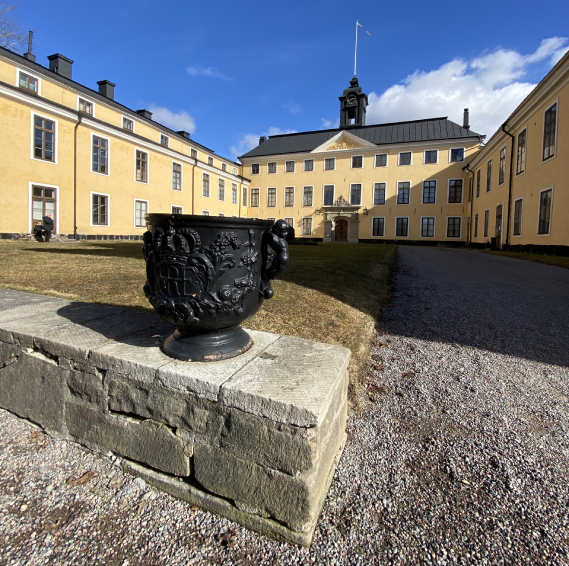Innergården på Ulriksdals slott med en pampig svartmålad järnurna i förgrunden.