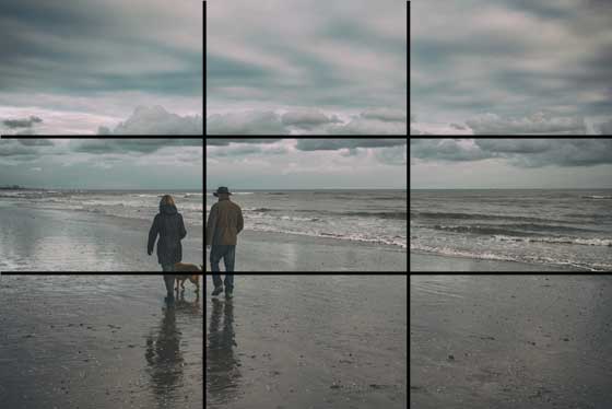 Fotografi som är indelat i nio rutor för att visa att ett promenerande par på stranden är placerat i en av  skärningspunkterna vilket ger en harmonisk bild.