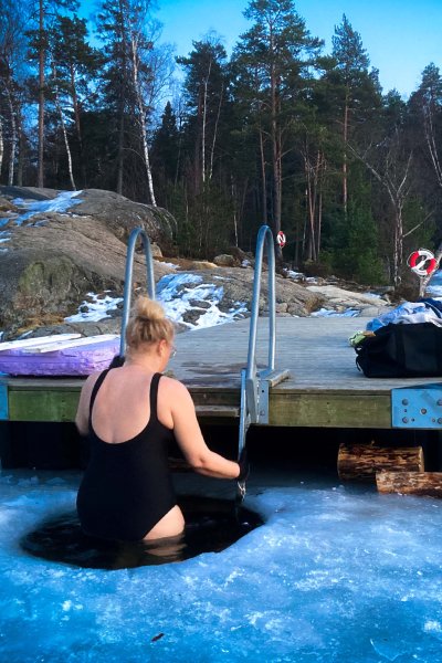 Elise Rensjö är på väg ner i isvaken iklädd svart baddräkt.